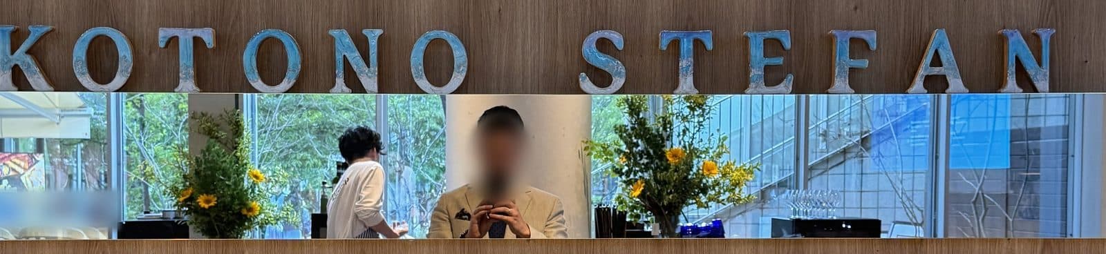 Handbemalte blaue Buchstaben mit den Namen Kotono und Stefan an einer Holzwand über einem Spiegel in der Hochzeitslocation