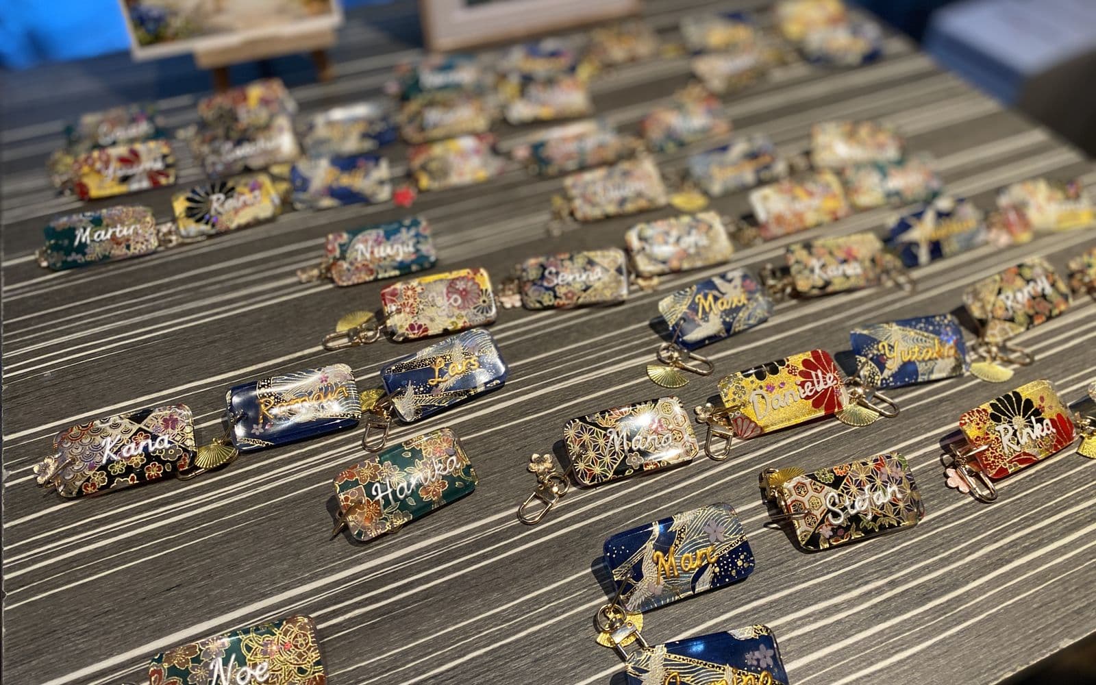 Nahaufnahme von handgemachten Hochzeits-Namensschildern aus traditionell gemustertem japanischem Papier, jedes mit dem Namen eines Gastes und einem kleinen Verschluss