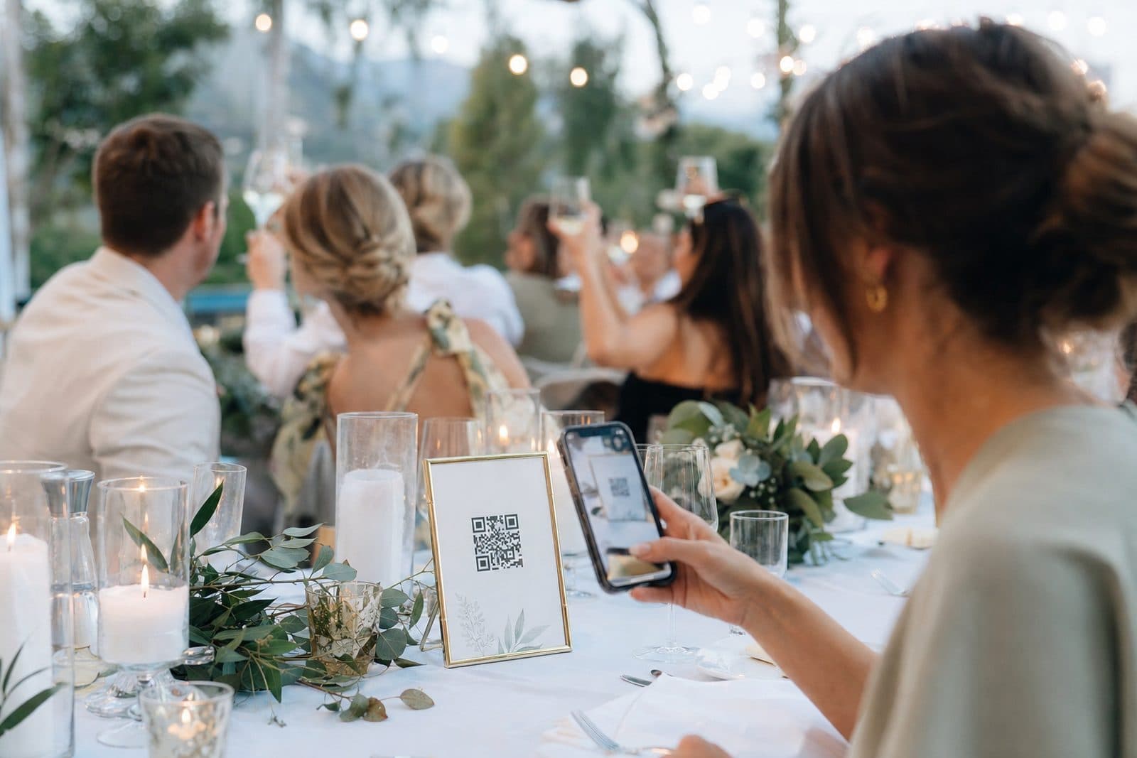 Un invitato che scansiona un QR code al tavolo del ricevimento per caricare le foto